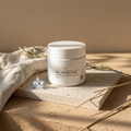Blue Nila Body Mask jar on travertine slab with linen, dried blue flowers, and dappled morning light.